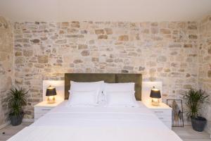 特罗吉尔Sobe Bartul Trogir的一间卧室配有一张带两盏灯的大型白色床。