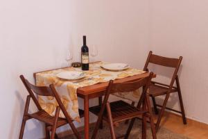 蒂瓦特Apartment Kjara的一张桌子、一瓶葡萄酒和两把椅子