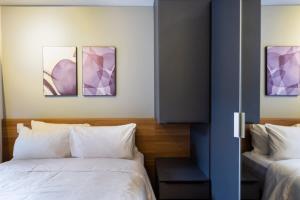 圣保罗BHomy Brooklin - 300m estacão da Brooklin BUR101的一间卧室设有两张床,墙上挂有紫色画作