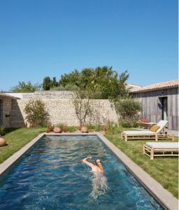 雷岛林滩Maisons 322 - L'Insolite的妇女在后院的游泳池游泳