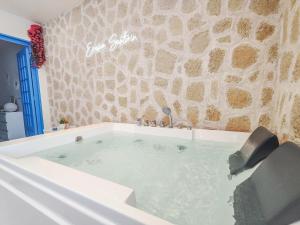 勒阿弗尔Évasion Santorin - Jacuzzi & Relax的石墙旁的浴缸