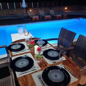 克拉法吉亚Drosoula Villa 3bdr private swimming pool的一张桌子,旁边放有盘子和酒杯
