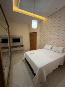 北茹阿泽鲁Casa Confort的卧室配有一张白色大床和电视。