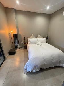约翰内斯堡On Fredman Drive的卧室配有一张带白色床单和枕头的大床。