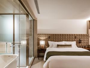 圣保罗Pulso Hotel Faria Lima的一间卧室设有一张大床和一个浴缸