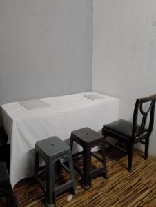 孟买Bapuji Paying Guest Santacruz West的一间设有两把椅子和一张桌子及一张白色桌子的房间