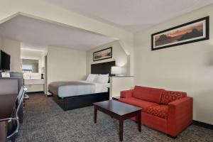 都柏林都柏林品质套房酒店的酒店客房,配有一张床和一张红色的沙发