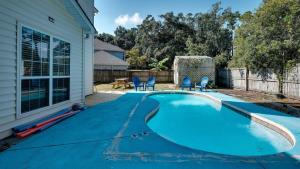 萨凡纳Mins to Savannah-Peachy Pied-à-Terre的一座房子旁的游泳池,配有蓝色的椅子