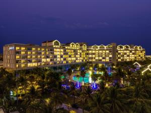 富国Radisson Blu Resort Phu Quoc的夜间带游泳池和棕榈树的度假村