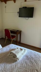 乔斯马拉尔Hostería Don Costa的一间卧室配有一张床、一张桌子和一把椅子
