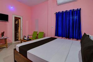 布巴内什瓦尔Khushi Guest House的一间卧室配有一张带蓝色窗帘的大床