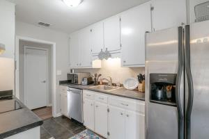 莫比尔Enchanting Forestwood Retreat的厨房配有白色橱柜和不锈钢冰箱