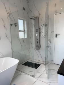 哈拉雷holiday villa的带淋浴和浴缸的白色浴室