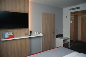吕姆朗Holiday Inn Express Zürich Airport, an IHG Hotel的配有一张床和一台平面电视的酒店客房