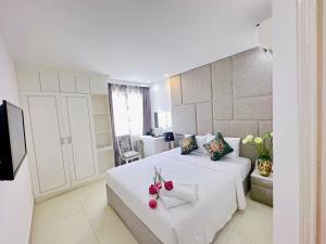 胡志明市Aodai Inn Saigon的卧室配有带鲜花的白色床