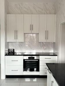 哈拉雷holiday villa的厨房配有白色橱柜和黑烤箱。