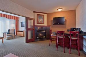 卡尔加里南卡尔加里智选假日酒店的酒店客房设有壁炉和红色椅子。