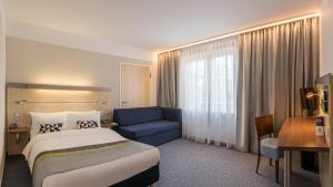 辛根辛根快捷假日酒店的酒店客房,配有床和蓝色的沙发