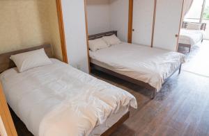宫古岛さつきあん的配有白色床单的客房内的两张床