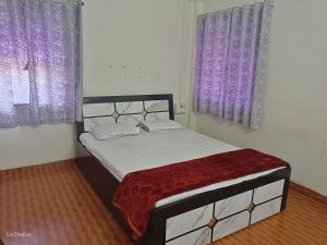 浦那OTE Dulis Den的卧室内的一张床位,配有紫色窗帘