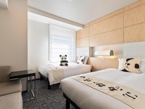 东京Mitsui Garden Hotel Ueno - Tokyo Reopened in July 2023的酒店客房设有两张床,上面有熊猫熊