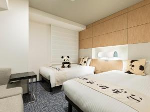 东京Mitsui Garden Hotel Ueno - Tokyo Reopened in July 2023的酒店客房设有两张床,上面有熊猫熊