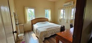坤西育府Armthong Resort的卧室配有床、桌子和窗户。