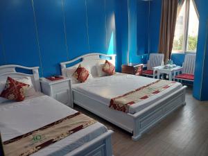 Tây Ninh那克酒店的蓝色墙壁客房的两张床