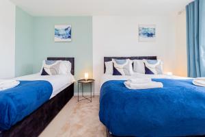 托顿Relaxing 4 Bedroom Retreat For Long Stays Fawley的蓝色和白色的客房内的两张床