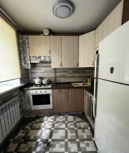 阿拉木图Ахметова 12的厨房配有木制橱柜和白色冰箱。