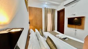 古尔冈Aura Luxury Studio Near Golf Course Road, Sector 57, Gurgaon的卧室配有一张床铺,墙上配有电视