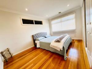 墨尔本Townhouse Near The World’s Coolest High st in 2024的一间卧室设有一张床和一个窗户,铺有木地板