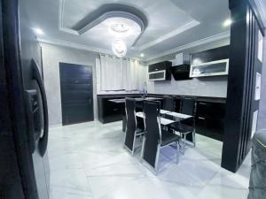 KasoaIrish Apartment的厨房配有黑色橱柜和一张带黑色椅子的桌子。