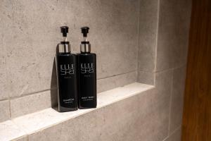 曼谷Woodstory Boutique Hotel的浴室内架上两瓶黑洗发水