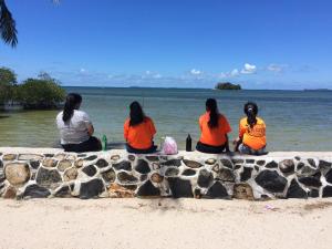 特鲁克巴库卢拉冒险度假村的坐在墙上看着水的四个女人
