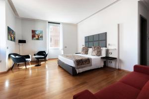 罗马玛切里诺套房旅馆的一间卧室配有一张床和一张红色的沙发