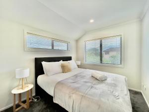 奥克兰Glendowie Brand-new comfortable 3 & 4-bedroom Houses的一间卧室设有一张大床和两个窗户。