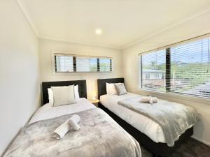 奥克兰Glendowie Brand-new comfortable 3 & 4-bedroom Houses的带2扇窗户的客房内的2张床