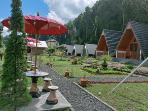 贝都古Popitan Garden Campground & Glamping Bedugul的花园配有红色遮阳伞和桌子