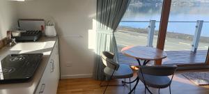 但尼丁Luxurious waterfront accommodation的一个带桌椅的厨房和一个阳台