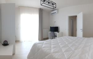 梅伦杜尼奥mya luxury rooms and wellness的一间白色卧室,配有床和电视