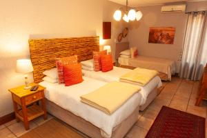 肯普顿帕克Safari Club Guest Lodge OR Tambo International Airport的酒店客房 - 带两张带橙色枕头的床