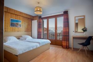 韦尔比耶圆厅酒店的一间卧室设有两张床、一张桌子和一个窗口。