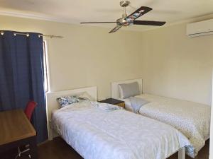 奥克兰Cozy Half Moon Bay Homestay的一间卧室配有两张床和吊扇