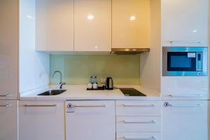 广州一呆公寓（广州保利世贸会展中心店）的厨房配有白色橱柜、水槽和微波炉