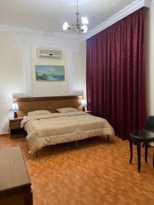安曼苏富拉套房酒店的一间卧室设有两张床和红色窗帘