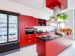 不莱梅Aparthotel Adagio Bremen City的一间厨房,配有红色橱柜和红色台面