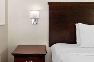 休斯顿Baymont by Wyndham Houston Brookhollow的酒店客房配有一张床和一张带台灯的桌子