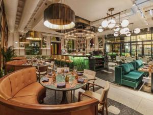 布达佩斯Pullman Budapest的一间带桌椅的餐厅和一间酒吧