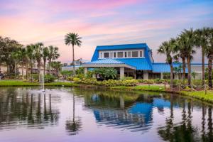 奥兰多Hilton Vacation Club Aqua Sol Orlando West的湖前棕榈树的房子